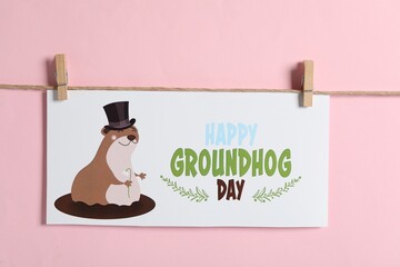 Happy Groundhog Day greeting card hanging on pink background