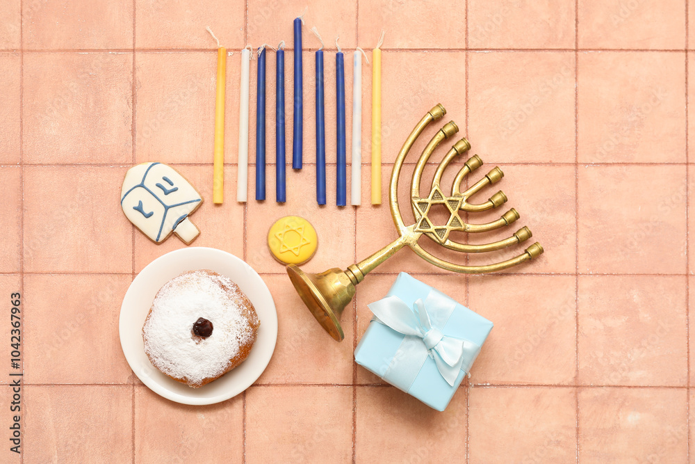 Composition for Hanukkah celebration with menorah, candles, gift box and donut on beige tiled background