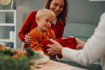 Curious child receiving a christmas gift from grandmother at home