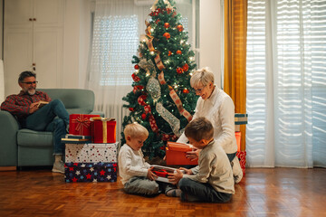 Wall Mural - Grandchildren opening christmas presents with grandmother