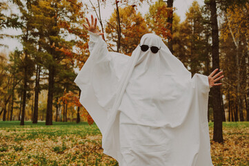 Wall Mural - Woman in a ghost costume against the backdrop of an autumn forest. Halloween costume. 