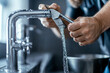 © Tondone - Close-up of hands repairing a kitchen faucet with running water, showcasing plumbing maintenance and home improvement skills.