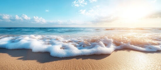 Wall Mural - Foamy wave crashing on sandy beach with bright blue sky and sun shining.