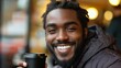 © ismel leal - Joven afro americano, Guan Free cano con una sonrisa y un café en la mano, sostiene una plaza y sonríe a la cámara. Concepto de buenos días y salud mental.