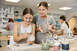 © JackF - Young female teacher explains to teenage girl student how to paint ceramic cup in workshop