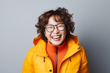 Wall Mural - Cheerful young woman in yellow jacket and eyeglasses laughing