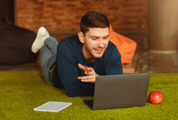 Poster - Freelance Career. Guy Using Laptop Making Video Call Communicating With Distant Clients Lying On Floor At Home.