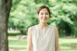 © buritora - 公園の木の下にいる若いアジア人女性（ボタニカル・オーガニック・自然・ナチュラル・森林浴）