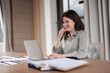 © wichayada - Young Businesswoman Analyzing Documents at Her Desk in a Modern Office Setting