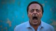 © Natcharat - A man from a Middle Eastern descent shouting in rage against a blue background