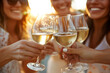 © Emanuel - Group of girlfriends toasting with white wine at sunset, close-up