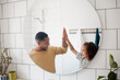 © peopleimages.com - Bathroom, high five and dad with child in mirror for dental hygiene, brushing teeth and cleaning. Health, family and father with girl for learning skincare, wellness and washing for morning routine