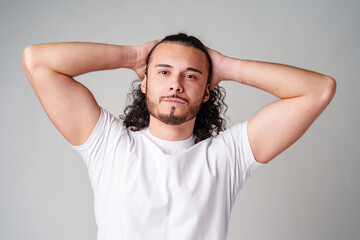 Young man with curly hair poses confidently against a plain background