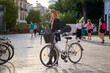 © Cavan Images - Woman in business attire stands beside a bicycle