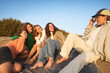 © Johnér - Young woman photographing female friends on rock during picnic