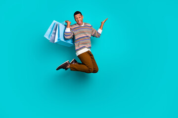 Wall Mural - Full body portrait of nice young man jump hold shop bags wear pullover isolated on turquoise color background