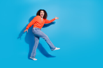 Wall Mural - Photo portrait of young latin funny lady with curly hairstyle in orange cardigan dancing silent going like cat isolated on blue color background