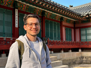 Smiling traveler in a traditional Korean courtyard on a sunny day