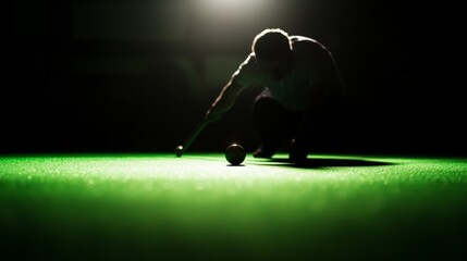 Player with cue stick in silhouette, focusing on the ball under a spotlight.