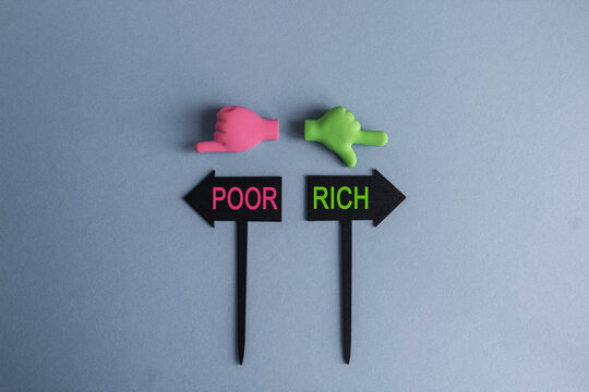 Rich and Poor symbol. BLACK ARROW-SHAPED PLAQUES WITH THE WORDS Rich or Poor. HANDS POINTING IN DIFFERENT DIRECTIONS. Blue background. Choice Decisions Direction Arrow Sign concept.