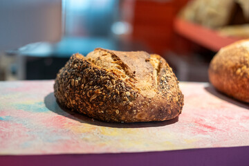 Freshly baked round bread of sunflower seeds isolated on the shop counter. Not sliced. Bakery, rustic traditional food concept. Side view. Ecological food.