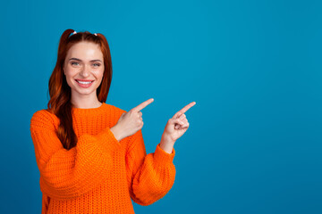 Photo portrait of attractive young woman point empty space dressed stylish knitted orange clothes isolated on blue color background