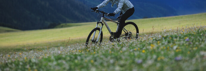 Wall Mural - Riding mountain bike on beautiful flowering grassland mountain top