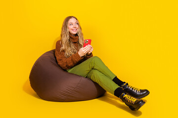 full size photo of pretty young woman hold phone look empty space isolated on yellow color backgroun