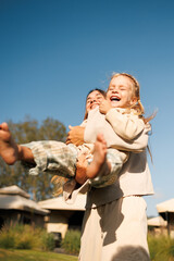 Canvas Print - Mom throws baby in her arms girl child laughs. Family outdoor recreation.