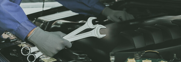 The mechanic works on the engine of the car in the garage, car repair service.	