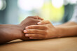 © peopleimages.com - People, holding hands and trust with empathy for support, care or understanding on wooden table. Closeup, interracial or touch with sympathy for listening, grief or loss in hope or faith together