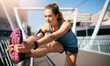 © peopleimages.com - Girl, stretching legs and bridge in city, morning and warm up with fitness, health and reflection in sunshine. Runner, woman and person with workout, muscle and ready to start exercise in Germany