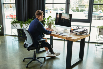 A determined young professional with an artificial limb is focused on his work at a stylish office desk.