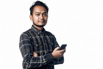 Young adult male is holding a smartphone in one hand and folding his arms, looking towards the camera with a confident expression