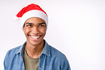 Closeup portrait of cheerful african young man teenager with toothy smile wearing Santa`s red hat in casual clothes preparing for New Year Christmas celebration winter holiday isolated on white