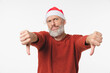 © InsideCreativeHouse - Disappointed sad angry caucasian mature middle-aged man wearing Christmas Santa Claus red hat showing thumbs down looking at camera isolated in white background
