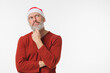 © InsideCreativeHouse - Pensive thoughtful caucasian mature middle-aged man in red Santa Claus Christmas hat thinking about buying presents gifts for celebration isolated in white background