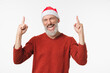 © InsideCreativeHouse - Happy cheerful caucasian mature middle-aged man wearing red Santa Claus hat pointing at copy space showing free space upwards isolated in white background
