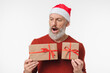 © InsideCreativeHouse - Shocked surprised caucasian mature middle-aged man in red Santa Claus hat holding Christmas New Year presents isolated in white background. Sale offer discount