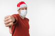 © InsideCreativeHouse - Sad disappointed caucasian mature middle-aged man in red Santa Claus hat and protective face mask against Coronavirus showing thumb down isolated in white background