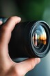 © Anton - Close-up of hand holding camera lens with reflections