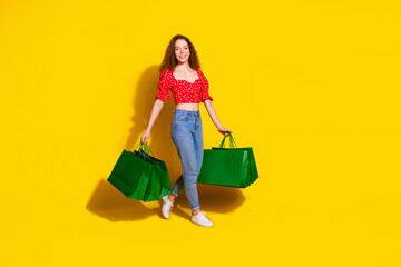 Wall Mural - Full size photo of pretty young girl hold shopping bags black friday wear trendy red outfit isolated on yellow color background