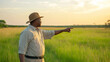© Bonsales - African farmer pointing towards the horizon in his field at sunset