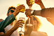 © peopleimages.com - People, hands and toast with alcohol in glass for outdoor, celebration and holiday together. Low angle, happy and group of friends with beverage in cheers for gathering, adventure and New Years party