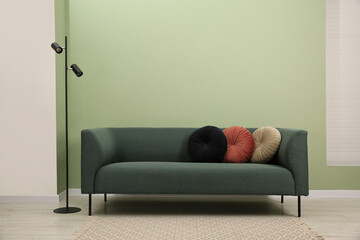 Wall Mural - Stylish sofa with pillows and lamp near green wall indoors