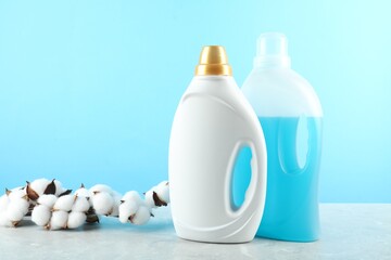 Poster - Laundry detergent in bottles and cotton flowers on grey marble table against light blue background