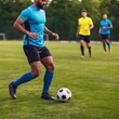 © LIGHTFIELD STUDIOS - Eye-level close-up of a multiracial male soccer player juggling the ball with his knees, with deep focus capturing the full field and teammates practicing in the background