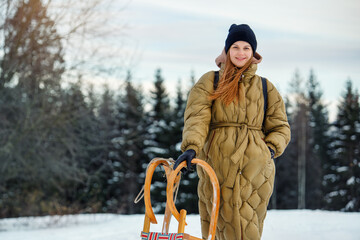 Portrait young adult happy woman enjoy having fun riding vintage wooden retro sledge mountain hill cold winter sunny day. Female joyful person sledding downhill outside at Christmas season