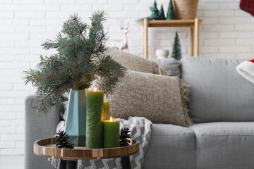 Wall Mural - Wooden coffee table with burning candles, fir branches and pine cones in festive living room, closeup. Christmas celebration