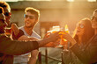 © peopleimages.com - People, happy and laughing with glass in toast for outdoor, celebration and adventure together. Summer, smile and group of friends with beverage in cheers for gathering, holiday and New Years party